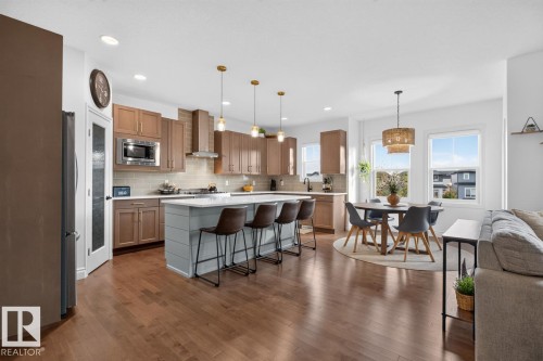 Wood-finish flooring throughout, kitchen featuring stainless steel appliances, light wood-finish cabinetry, and a light gray subway tile backsplash - 21 Altadena Point(E), Sherwood Park, AB 
