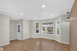 Wood-finish flooring throughout, recessed ceiling lighting, bay window, front entry door with glass panels, and a wood-slat accent wall - 