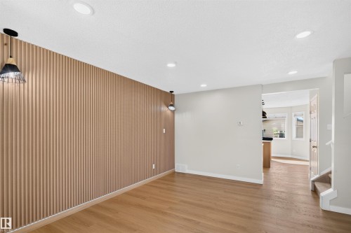 Accent wall with vertical wood paneling, wood-finish flooring, recessed ceiling lighting, and pendant light fixtures - 4409 150 Avenue Nw, Edmonton, AB 