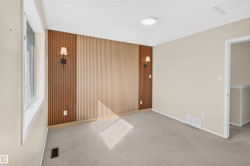 Accent wall with vertical wood paneling and two sconce lights, neutral wall paint, and carpet flooring - 