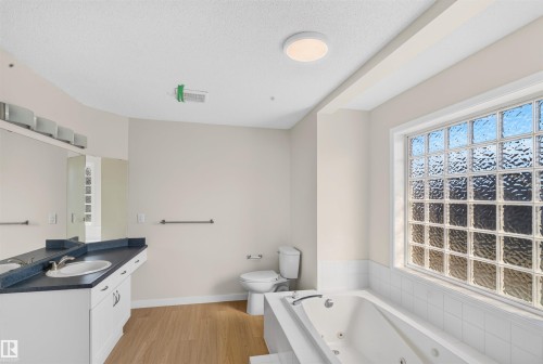Double vanity with integrated sinks, a built-in jetted tub, and a large glass block window - 4409 150 Avenue Nw, Edmonton, AB 