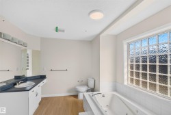 Double vanity with integrated sinks, a built-in jetted tub, and a large glass block window - 