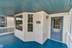 Covered porch with a blue-painted floor and ceiling, white railing, and exterior wall paneling - 