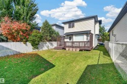 Spacious backyard featuring a wood-finish deck with privacy screens, a chain-link fence, and a manicured lawn - 