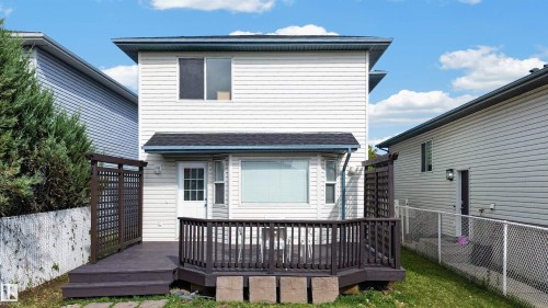 Rear exterior with an expansive wooden deck, white siding, and a bay window - 4409 150 Avenue Nw, Edmonton, AB 