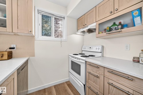 Wood-finish flooring with light-toned cabinetry, light countertops, and a white range - 161 Lancaster Terrace Nw, Edmonton, AB 