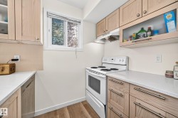 Wood-finish flooring with light-toned cabinetry, light countertops, and a white range - 