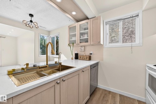 Integrated gold-finish sink with a matching faucet, light wood-finish cabinetry, white countertops, and wood-finish flooring - 161 Lancaster Terrace Nw, Edmonton, AB 