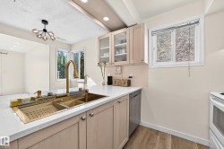 Integrated gold-finish sink with a matching faucet, light wood-finish cabinetry, white countertops, and wood-finish flooring - 