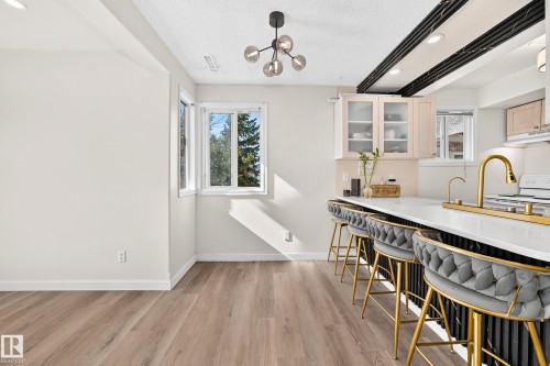 Wood-finish flooring, recessed lighting, modern chandelier, double window, and kitchen island with built-in storage - 161 Lancaster Terrace Nw, Edmonton, AB 