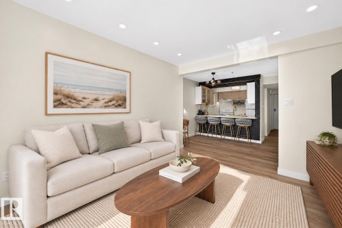 Recessed lighting illuminates the open-concept living space, featuring wood-finish flooring and a kitchen with a breakfast bar - 161 Lancaster Terrace Nw, Edmonton, AB 