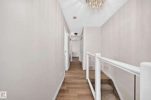 Hallway featuring wood-finish flooring, light neutral paint, and white trim - 161 Lancaster Terrace Nw, Edmonton, AB 