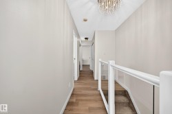 Hallway featuring wood-finish flooring, light neutral paint, and white trim - 