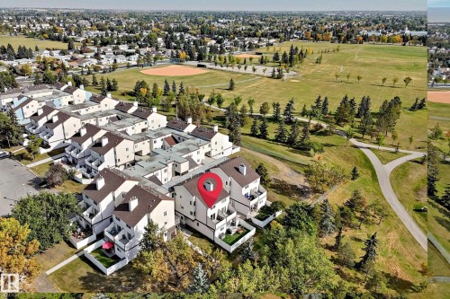 Townhouse community featuring private balconies, individual patios, and direct access to expansive green spaces with paved pathways - 161 Lancaster Terrace Nw, Edmonton, AB 