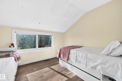 Sloped ceiling, wood-finish flooring, and white trim window - 