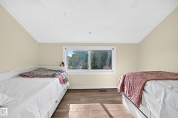 Room featuring wood-finish flooring, a window with white trim, and a built-in daybed with storage drawers - 