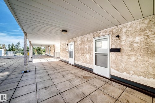 Covered exterior walkway featuring a textured wall finish, white exterior doors, and a tiled surface - 161 Lancaster Terrace Nw, Edmonton, AB 