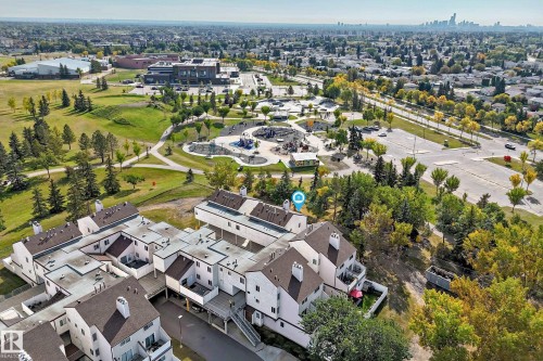 Townhome community with pitched and flat roofs, private balconies, paved pathways, and surrounding green spaces - 161 Lancaster Terrace Nw, Edmonton, AB 