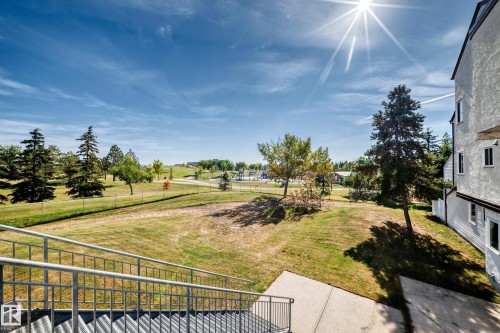 Exterior building with multiple windows, metal staircase with handrails, concrete landing, and a grassy expanse with mature trees - 161 Lancaster Terrace Nw, Edmonton, AB 