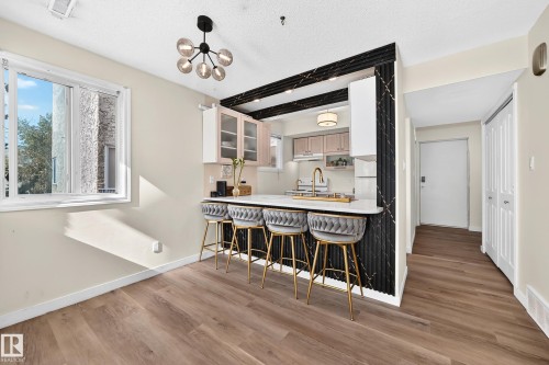 Open-concept living area with wood-finish flooring, a modern chandelier, and a bright window - 161 Lancaster Terrace Nw, Edmonton, AB 