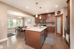 Kitchen featuring wood-finish flooring, dark wood cabinetry, a central island with a light-toned countertop, and stainless steel appliances - 