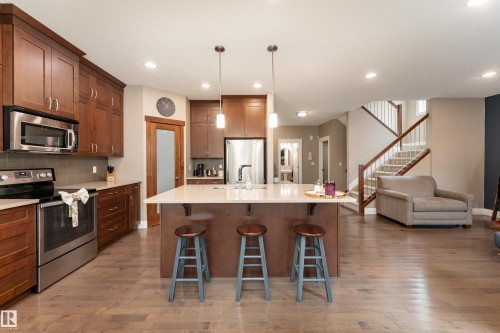 Kitchen featuring wood-finish flooring, a central island with countertop, recessed lighting, and stainless steel appliances - 6613 31 Avenue, Beaumont, AB 