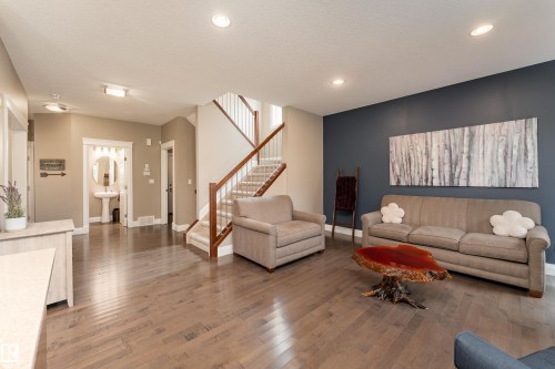 Wood-finish flooring throughout, recessed lighting, and a staircase with wood handrails and carpeted treads - 6613 31 Avenue, Beaumont, AB 
