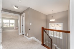 Plush carpeted hallway with an arched doorway, leading to a room with multiple windows - 