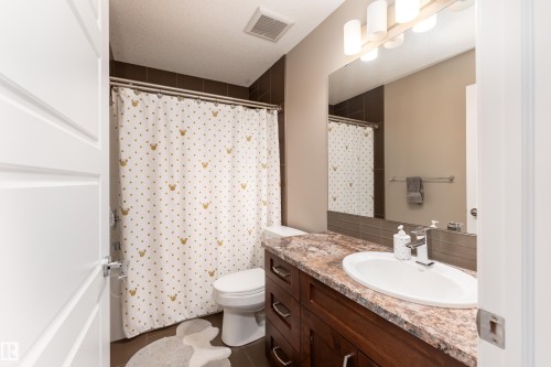 Integrated vanity with an undermount sink, a countertop with a polished finish, and a large mirror - 6613 31 Avenue, Beaumont, AB 