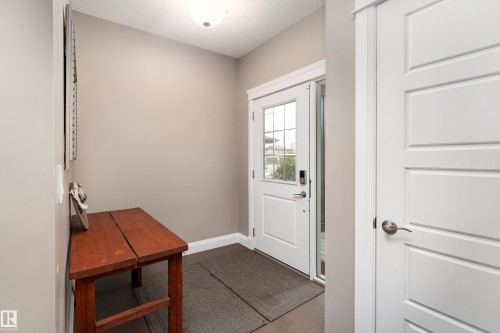 Entryway featuring a paneled door with glass inserts, transom window, and a sleek ceiling-mounted light fixture - 6613 31 Avenue, Beaumont, AB 