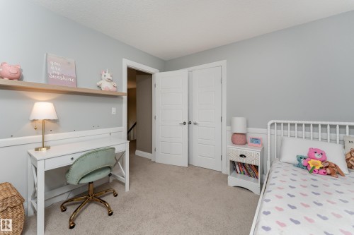 Plush carpeting, light grey wall paint, two white paneled doors, and a built-in floating shelf - 6613 31 Avenue, Beaumont, AB 