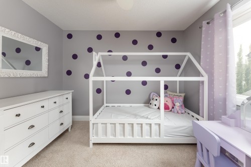 Carpeted room with a white built-in bed frame, a built-in dresser with dark hardware, and a window with light purple curtains - 6613 31 Avenue, Beaumont, AB 