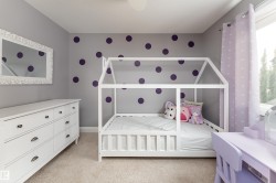 Carpeted room with a white built-in bed frame, a built-in dresser with dark hardware, and a window with light purple curtains - 