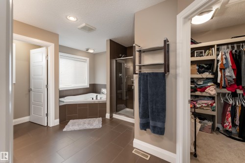 Corner soaking tub with tiled surround, glass-enclosed shower, and built-in closet organization - 6613 31 Avenue, Beaumont, AB 
