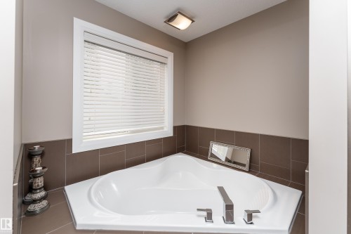 Corner soaking tub with polished chrome fixtures and surround tile - 6613 31 Avenue, Beaumont, AB 
