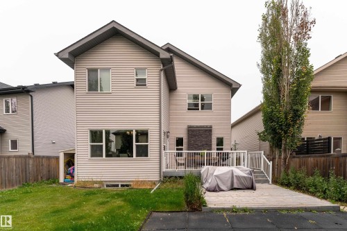 Rear exterior featuring horizontal siding, multiple windows, a stone accent wall, and a wood deck with white railings - 6613 31 Avenue, Beaumont, AB 