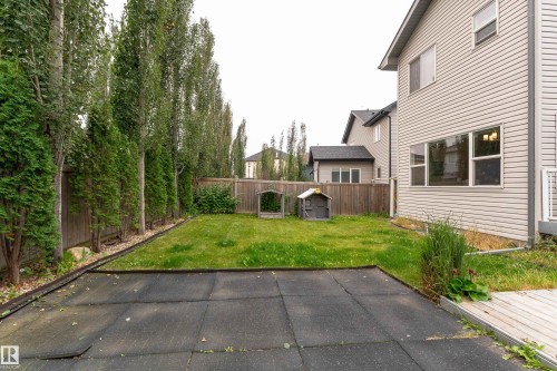 Rear exterior featuring siding, upper and lower windows, wood fencing, and mature trees - 6613 31 Avenue, Beaumont, AB 