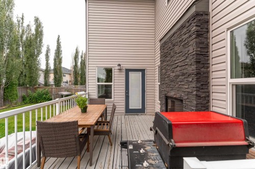 Outdoor deck with a white railing, wood-finish decking, and an exterior fireplace featuring stacked stone - 6613 31 Avenue, Beaumont, AB 
