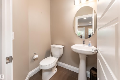 Pedestal sink, wall-mounted mirror, overhead lighting, and a white toilet - 6613 31 Avenue, Beaumont, AB 