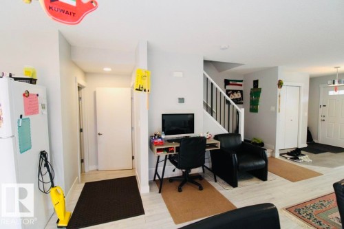 Light wood-finish flooring throughout, white interior doors, and a staircase with black metal balusters - 17440 77 Street Nw, Edmonton, AB 