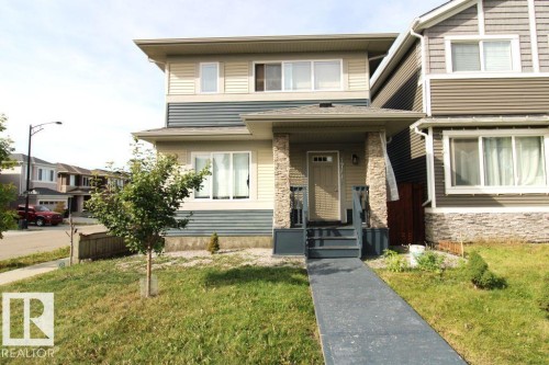 Two-story siding exterior with stone pillar accents, covered front porch, and ground-level windows - 17440 77 Street Nw, Edmonton, AB 