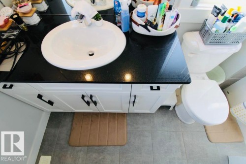 White vanity with dark hardware, black countertop, and integrated white sink - 17440 77 Street Nw, Edmonton, AB 