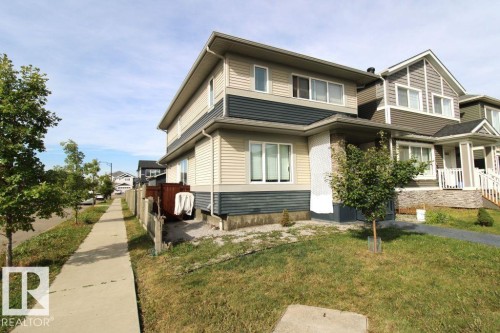 Two-story residence featuring light and dark siding, a covered porch with stone detailing, and multiple windows - 17440 77 Street Nw, Edmonton, AB 