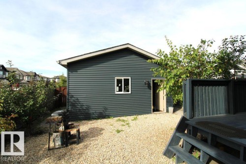 Detached structure with horizontal siding and a single window, featuring a gravel ground cover and partial wood decking - 17440 77 Street Nw, Edmonton, AB 