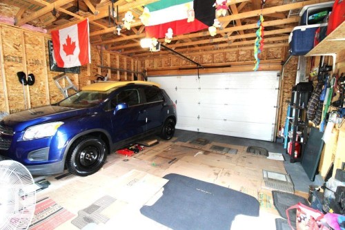 Single-car garage with a paneled overhead door, exposed wood framing, and wood-paneled walls - 17440 77 Street Nw, Edmonton, AB 