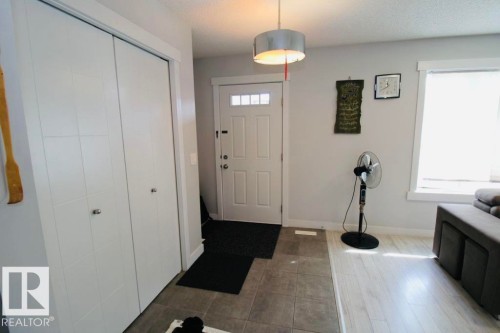 Entry area featuring a solid panel door with upper window panes, tile flooring, and wood-finish flooring - 17440 77 Street Nw, Edmonton, AB 