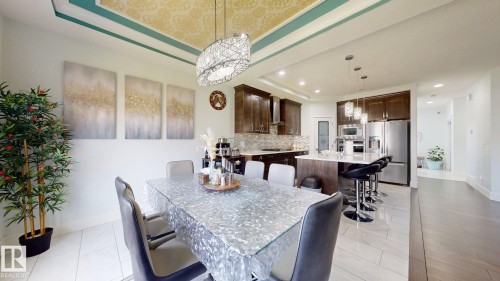 Recessed lighting throughout, two-tone tray ceiling with decorative inlay, wood-finish cabinetry, stainless steel appliances, and a kitchen island with seating - 1103 30 Street Nw, Edmonton, AB 
