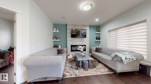 Hardwood-finish flooring, recessed lighting, accent wall with built-in shelving, fireplace with stone surround, and modern light fixture - 1103 30 Street Nw, Edmonton, AB 
