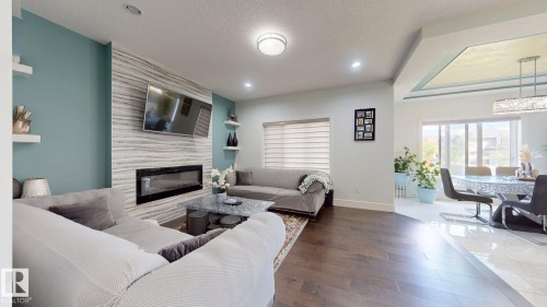 Living room featuring a textured accent wall with an integrated linear fireplace, recessed lighting, and wood-finish flooring - 1103 30 Street Nw, Edmonton, AB 