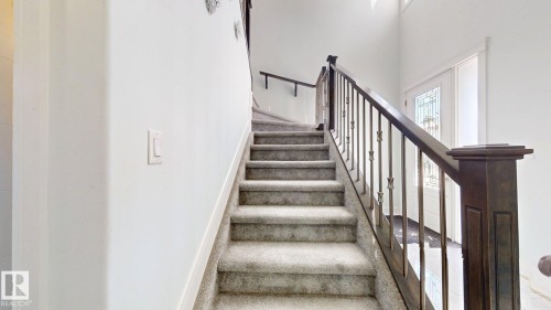 Carpeted staircase with dark wood-finish newel post and balusters - 1103 30 Street Nw, Edmonton, AB 